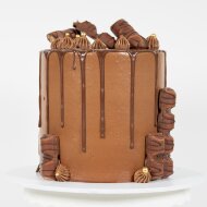 Chocolate themed cake with Kinder Buenos, chocolate drips, gold sprinkles, and piped dollops